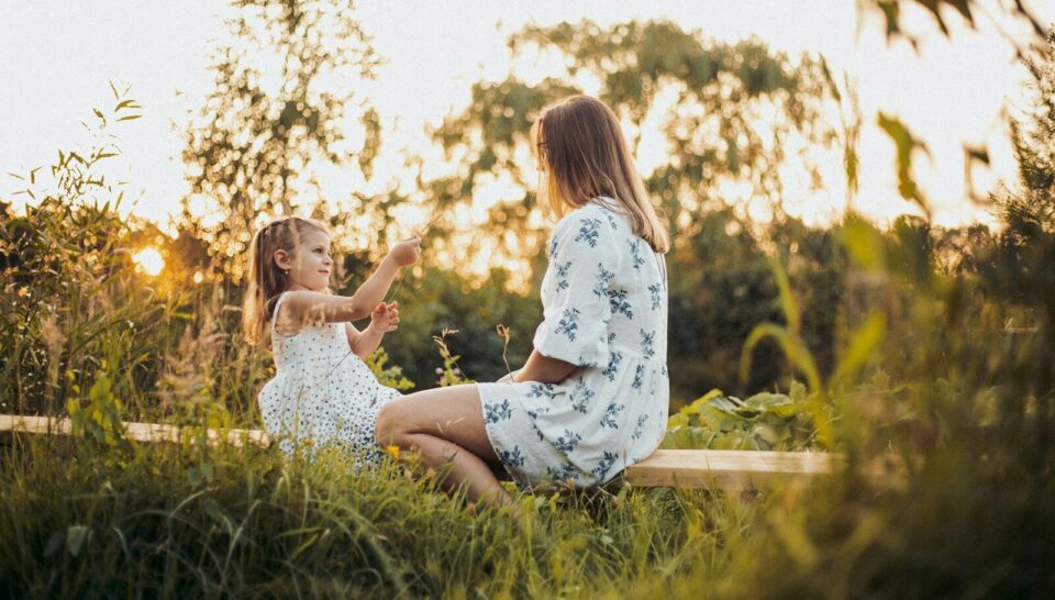 a woman and a little girl sitting on a bench