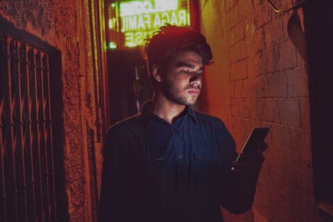 man in black dress shirt standing near red brick wall