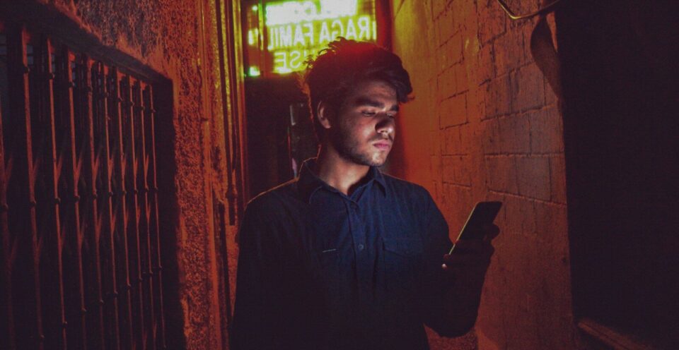 man in black dress shirt standing near red brick wall