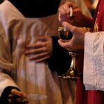 A priest is holding a glass of wine