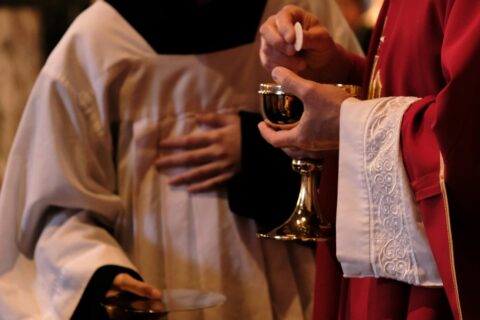 A priest is holding a glass of wine