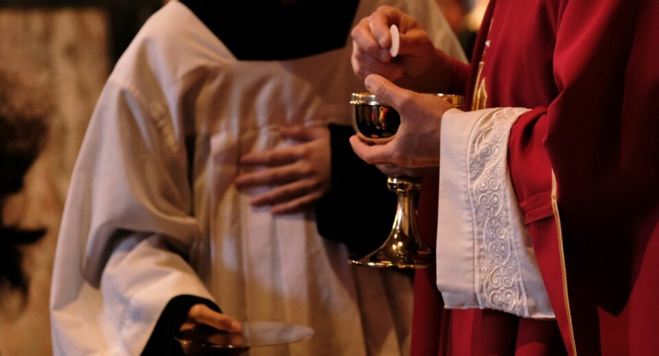 A priest is holding a glass of wine