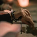 Hands holding rosary beads with soft light