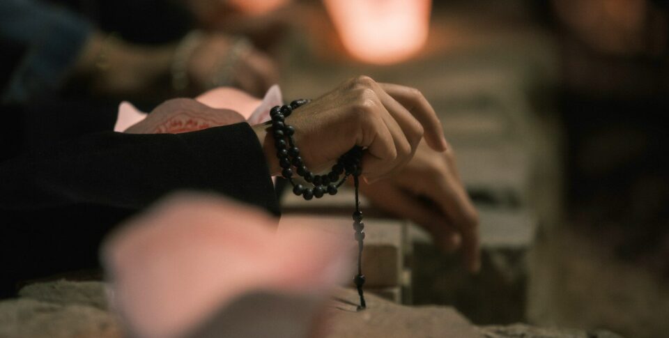 Hands holding rosary beads with soft light