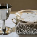 Elegant display of a silver chalice with wine and wafers in a sacred setting, symbolizing the Eucharist.