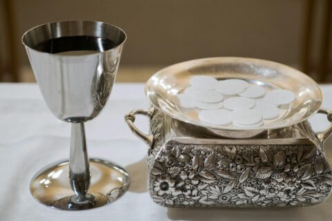 Hostija pala tijekom pričesti? Evo što učiniti Elegant display of a silver chalice with wine and wafers in a sacred setting, symbolizing the Eucharist.