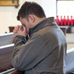 Muškarac kleči u crkvi i moli u tišini, simbol osobne molitve, mira i povezanosti s Bogom