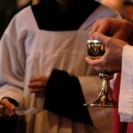 A priest is holding a chalice in a church