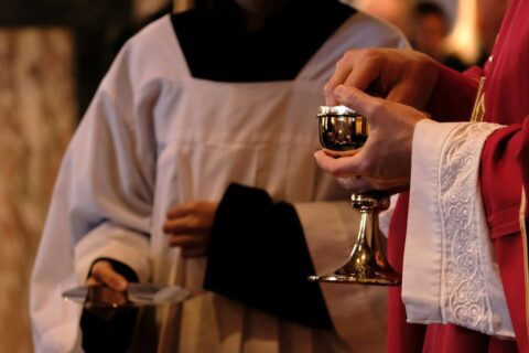 A priest is holding a chalice in a church