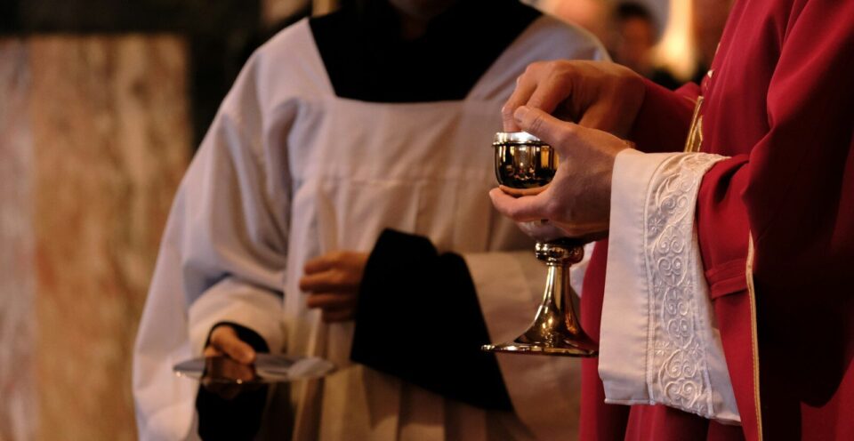 A priest is holding a chalice in a church
