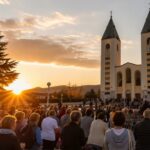Hodočasnici okupljeni u molitvi ispred crkve sv. Jakova i Gospina kipa u Međugorju tijekom zalaska sunca