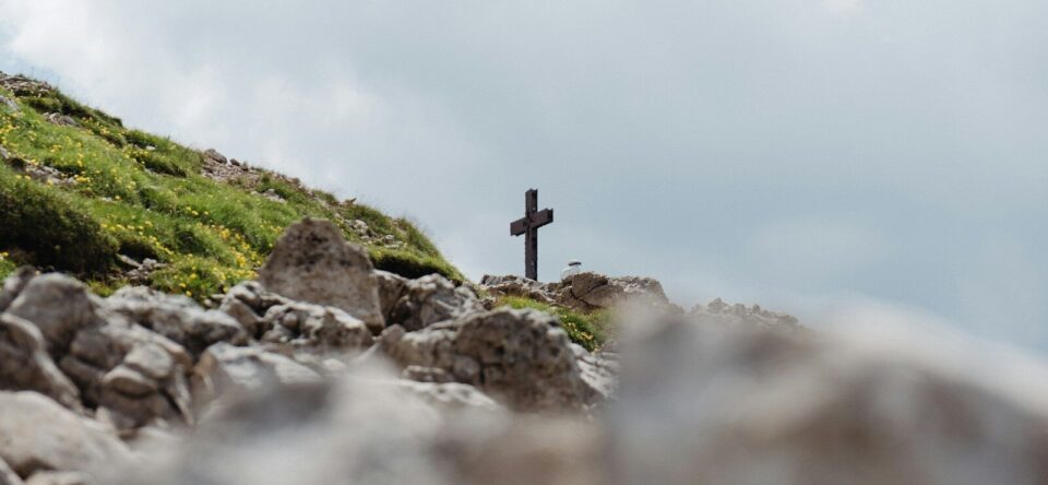 black cross on gray rocks under white sky during daytime