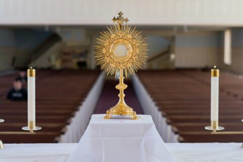 A golden monstrance with candles on an altar.