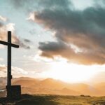 a cross sitting on top of a lush green hillside