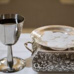 Elegant display of a silver chalice with wine and wafers in a sacred setting, symbolizing the Eucharist.