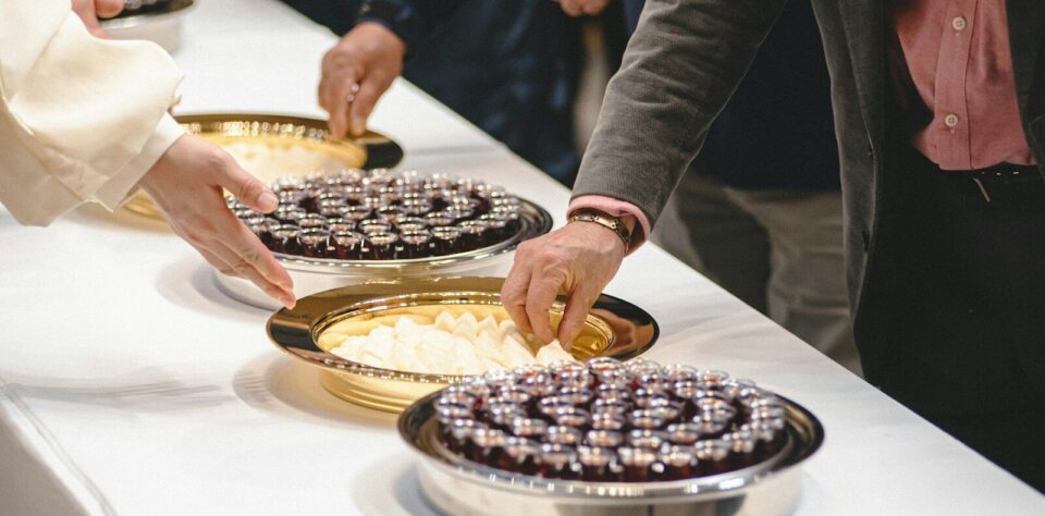 People reaching for desserts on a table.