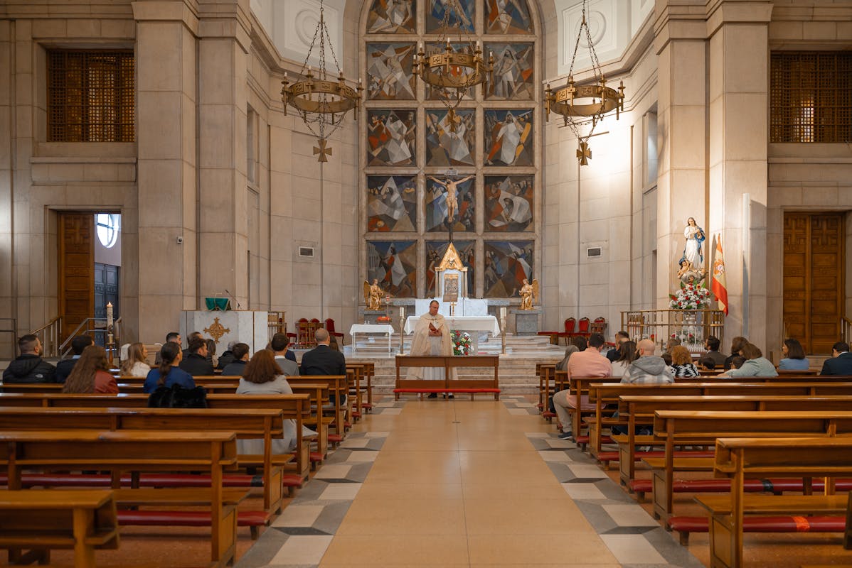 A serene church interior with people attending a religious ceremony led by a priest.