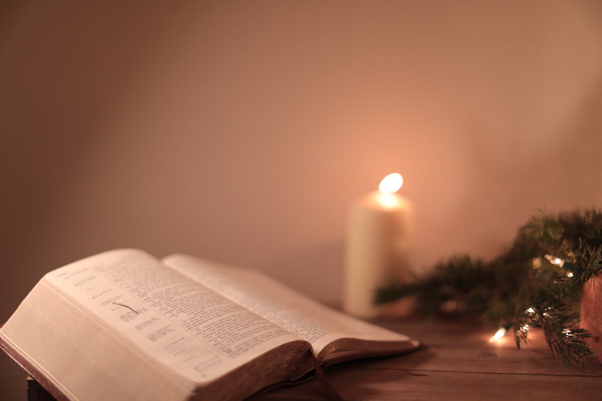 Open Bible with candle and festive greenery creates a serene ambiance.