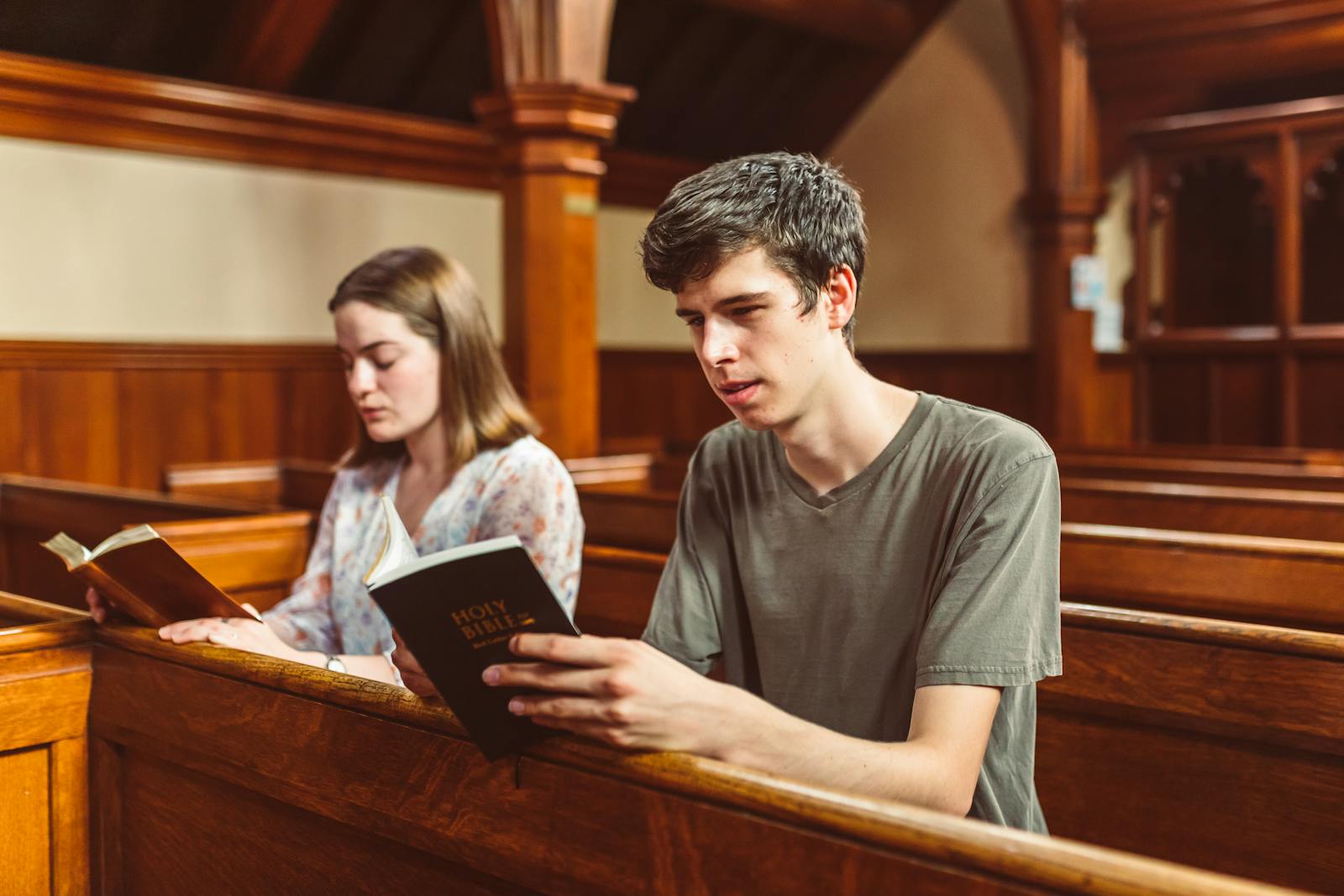 Two young adults reading the Holy Bible inside a church, reflecting faith and spirituality.