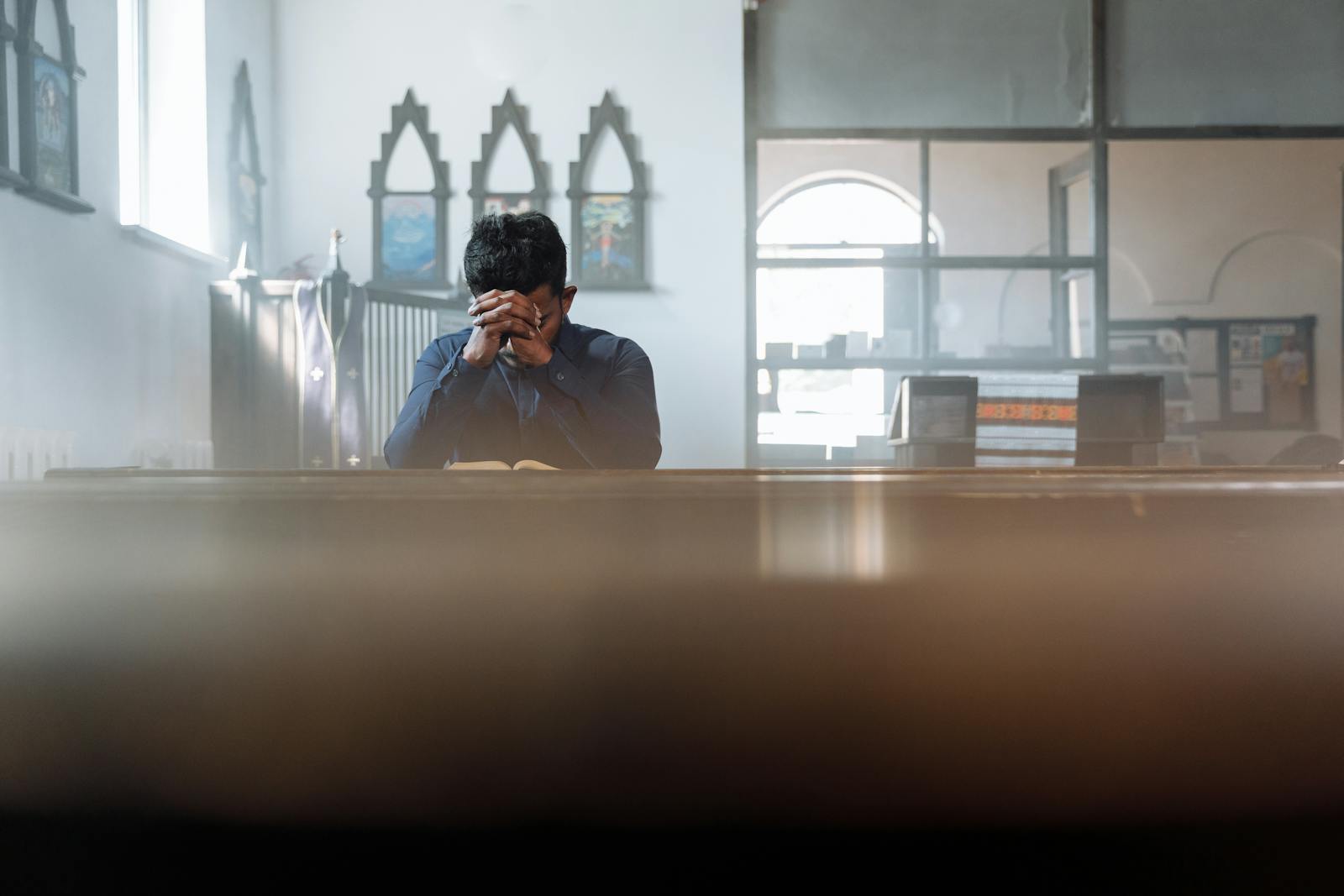 A man in prayer in a sunlit room, reflecting spirituality and peace.