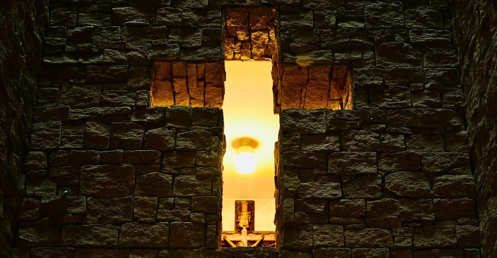 A cross-shaped window with light shining through.