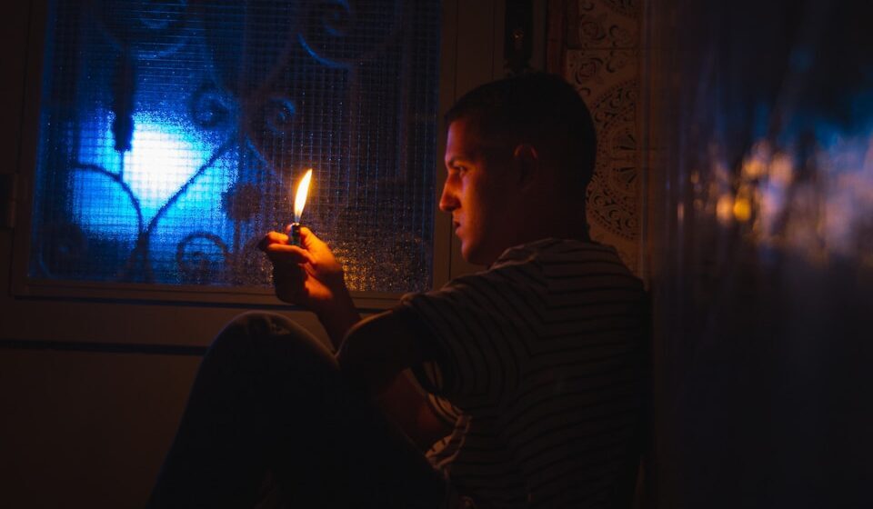 a man sitting in a dark room holding a lit candle