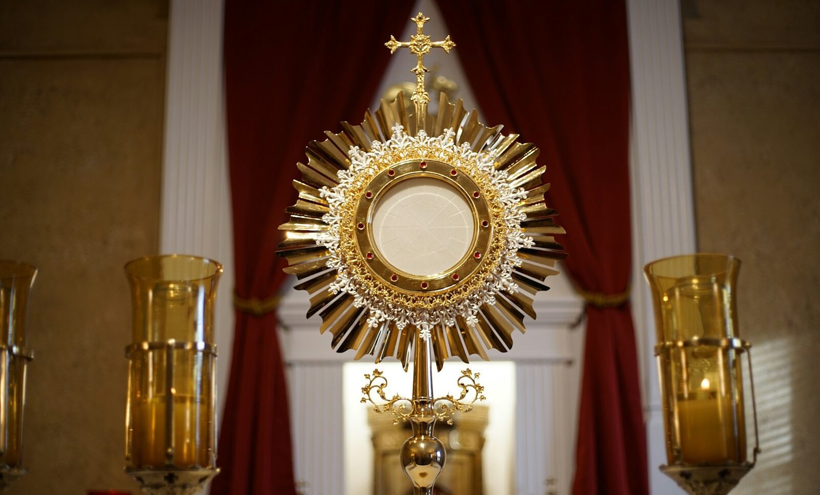 a golden cross and two candles in front of a window