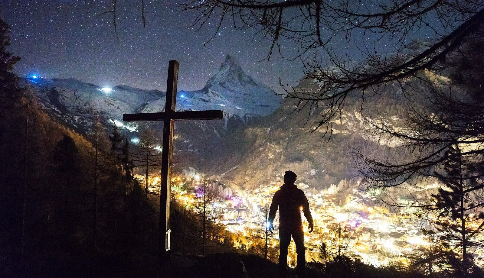 man standing near cross during night