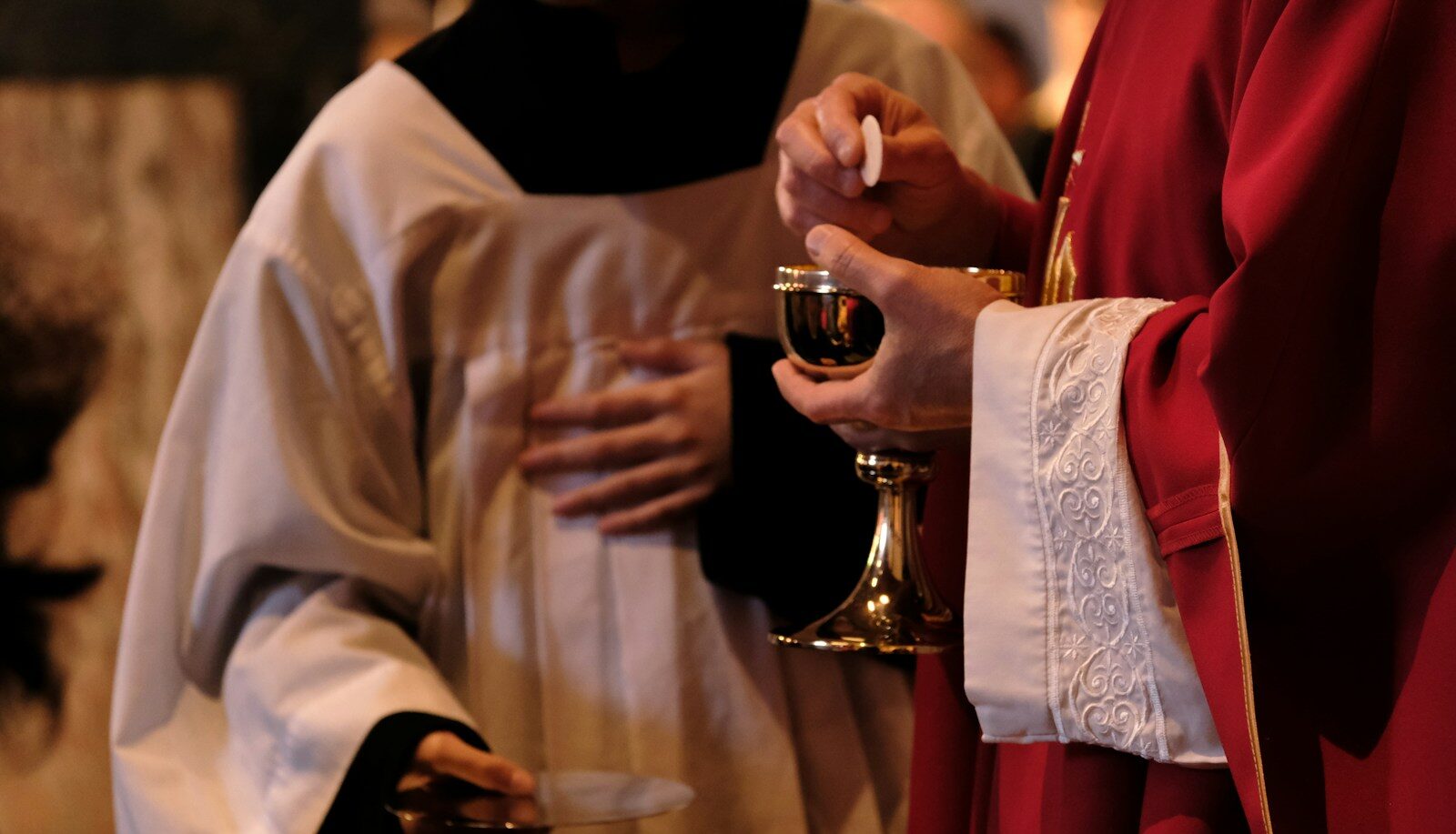 A priest is holding a glass of wine