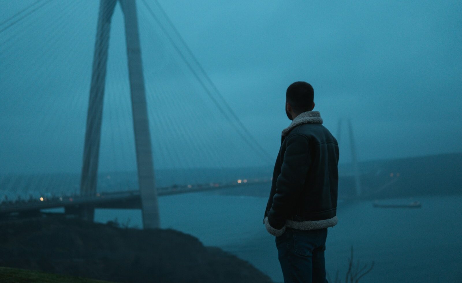 a man standing in front of a bridge at night