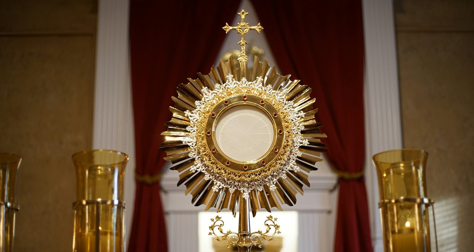 a golden cross and two candles in front of a window