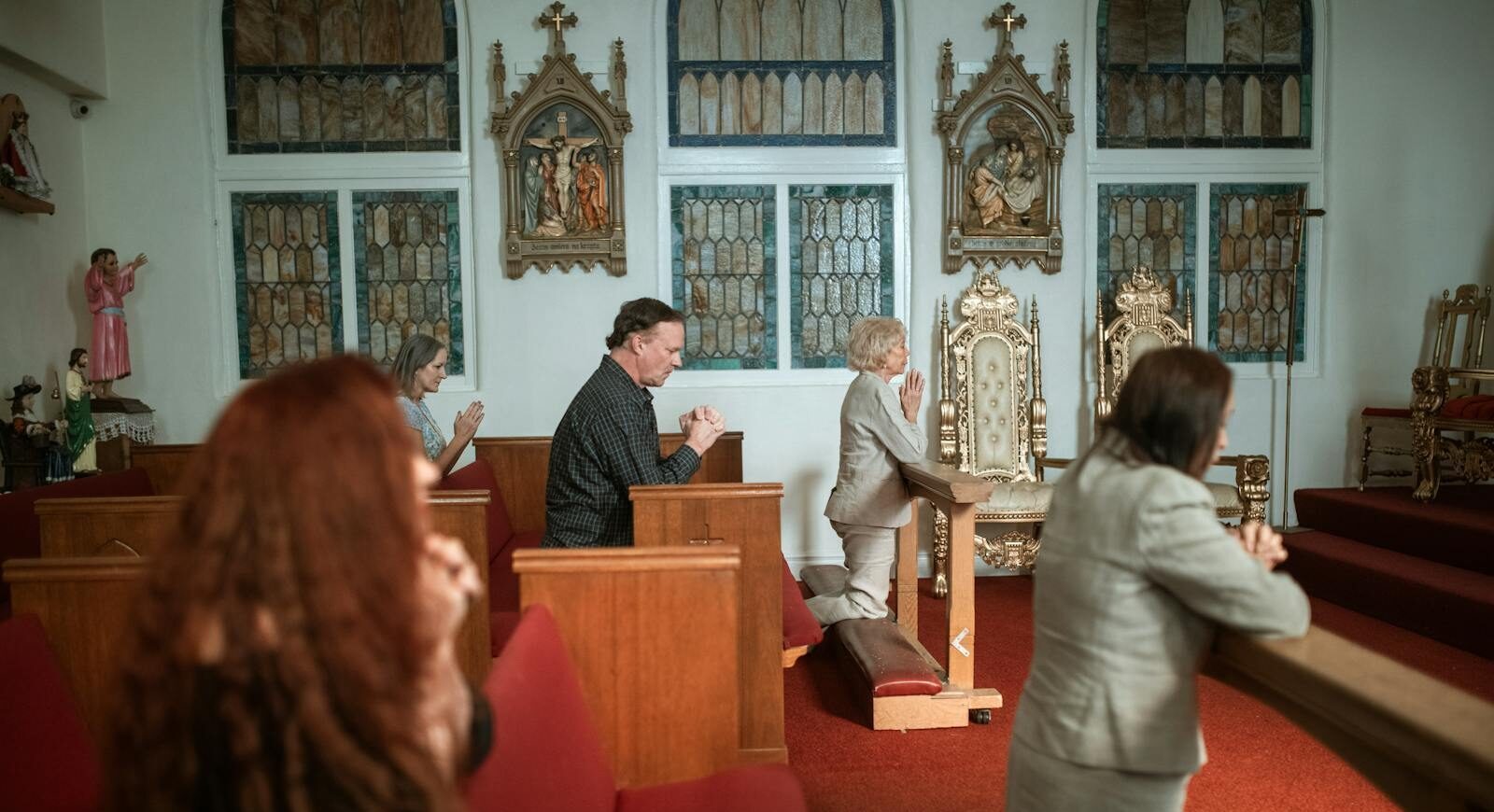 Group of people solemnly praying inside a beautifully adorned historic church, showcasing devotion and spirituality.