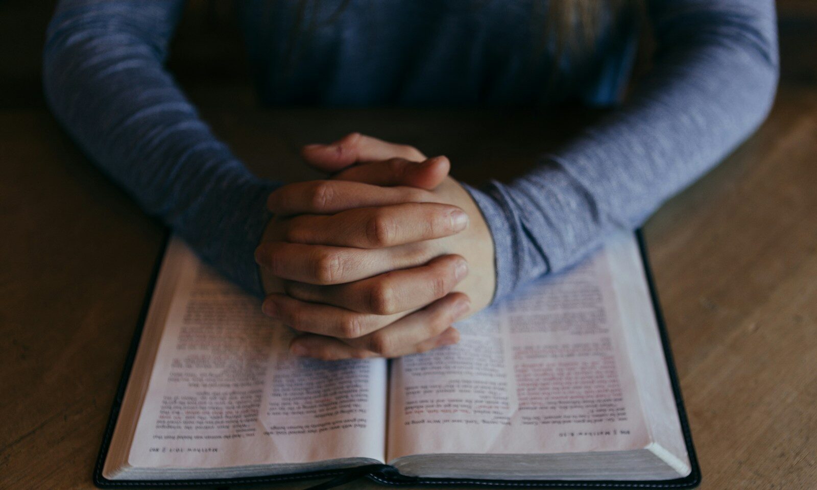 man holding his hands on open book