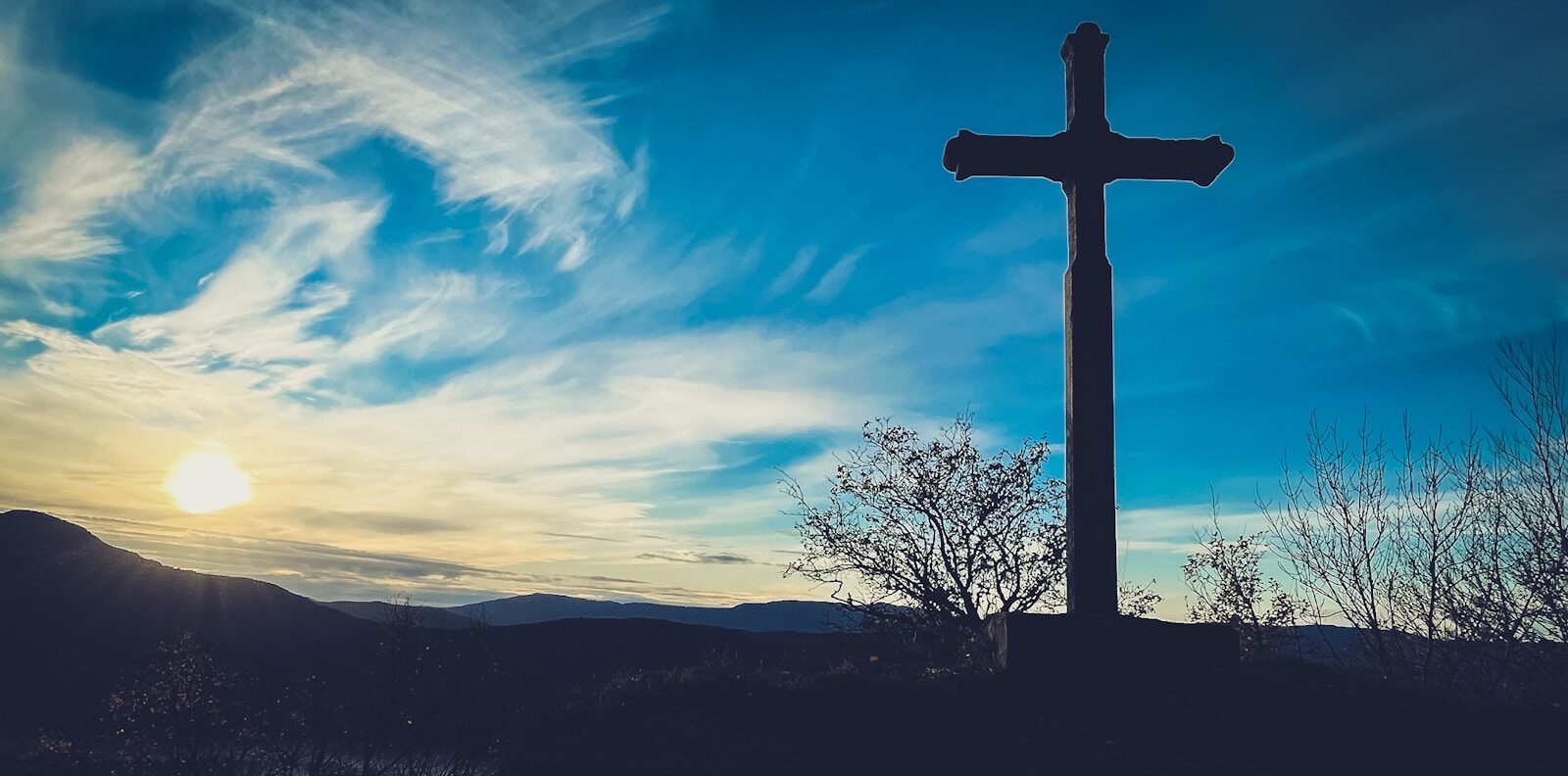 a cross on top of a hill with a sky background