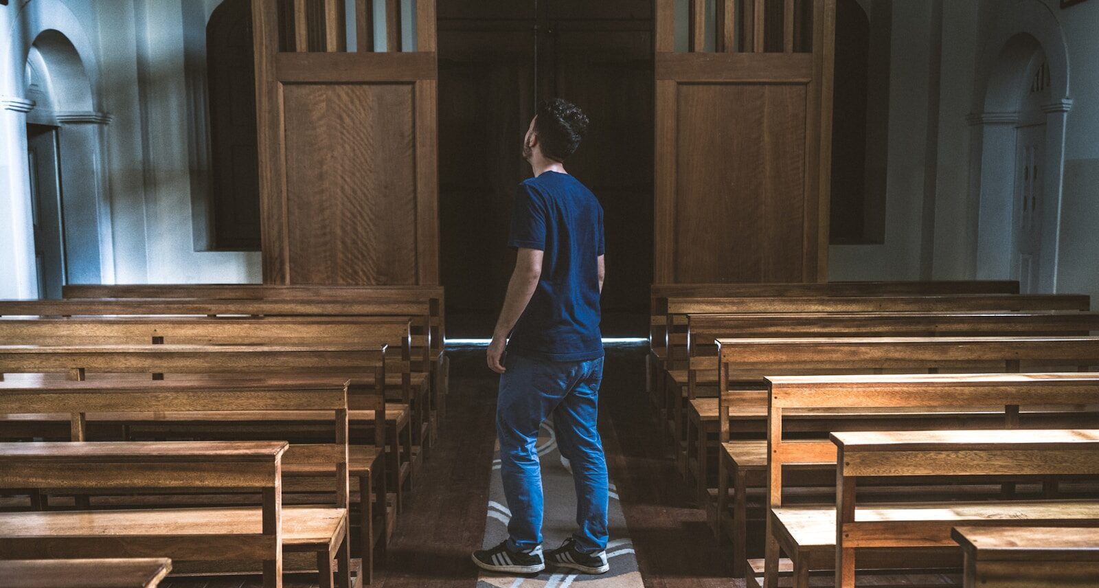a man standing in a church looking at the pews