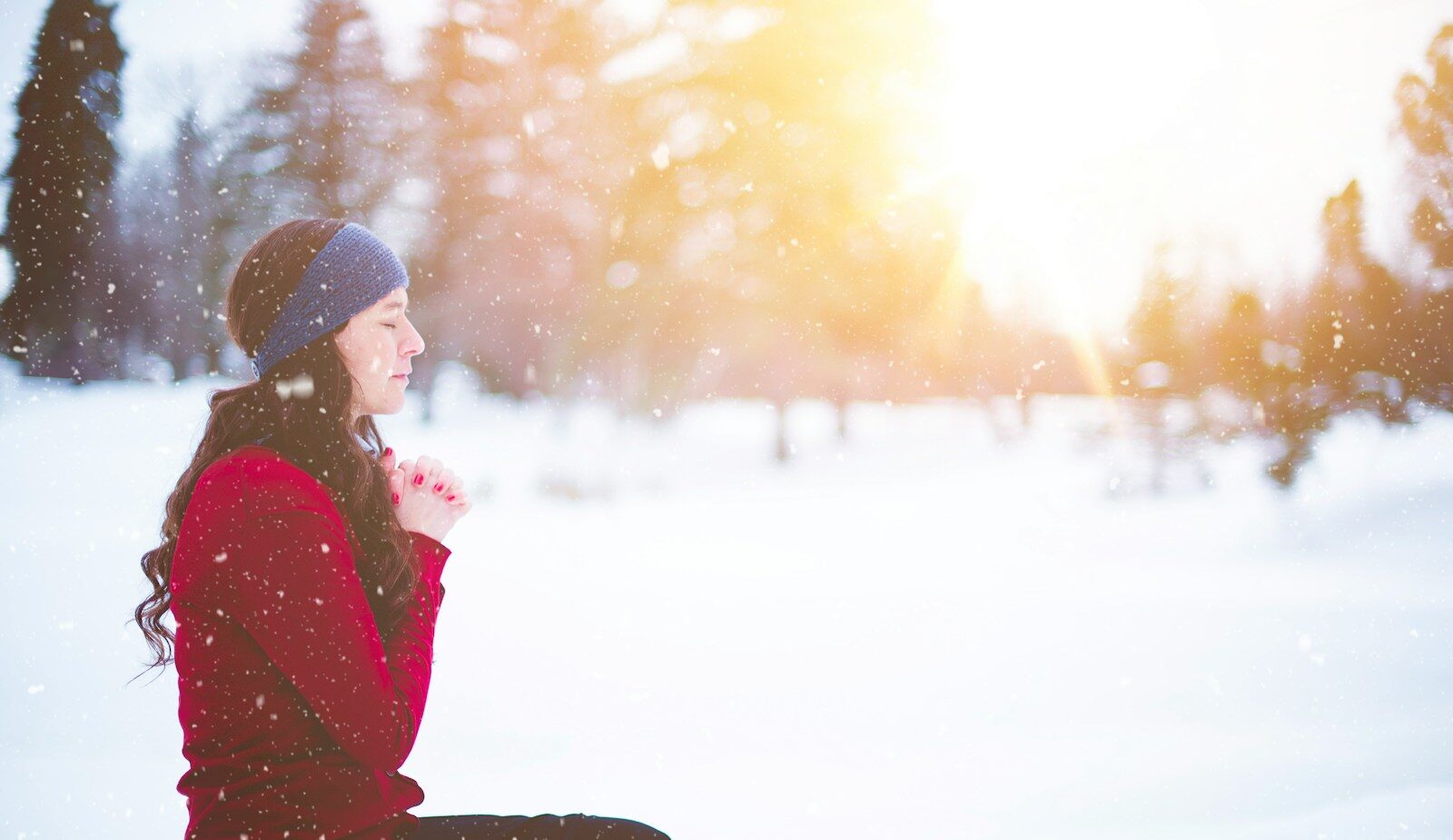 woman sitting with closed eyes surrounded by snow