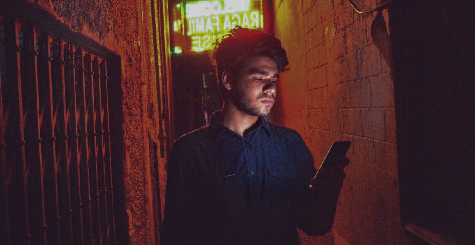 man in black dress shirt standing near red brick wall
