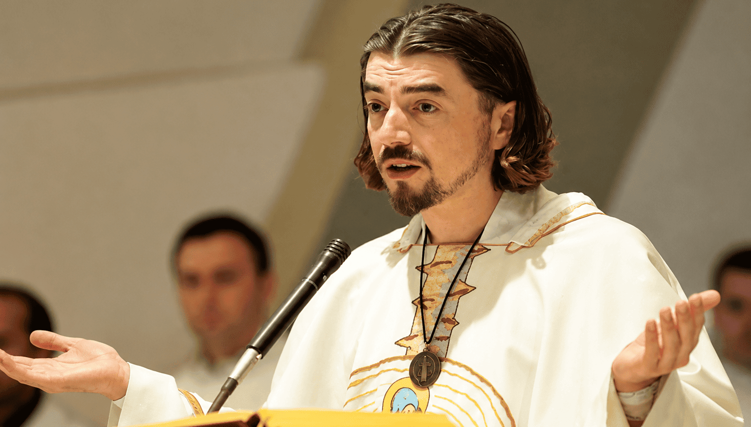 Vlč. Zlatko Sudac tijekom propovijedi govori vjernicima s raširenim rukama za ambonom u crkvi.
