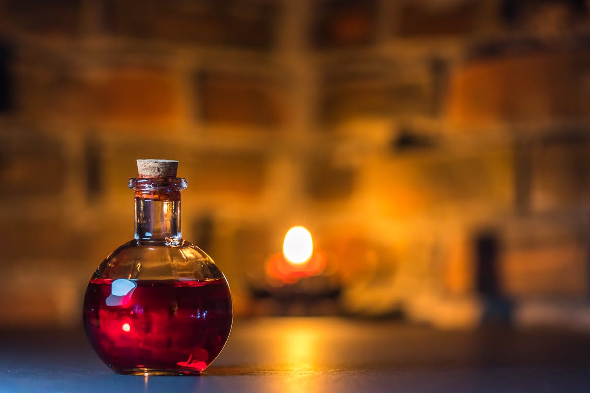 A mystical potion bottle glows warmly in candlelight against a rustic brick background.