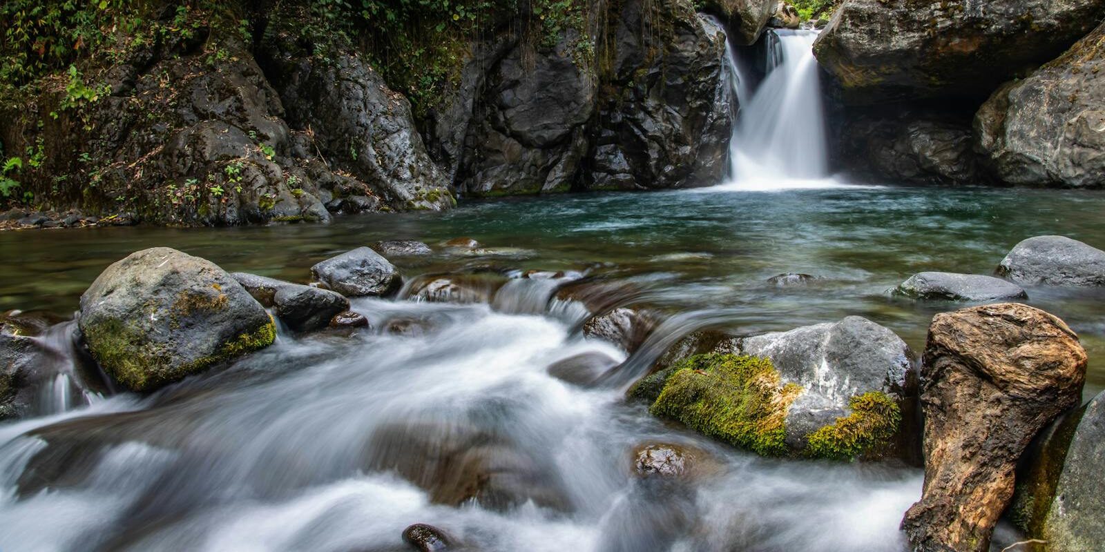 Tranquil waterfall cascading through mossy rocks in a lush forest setting. Perfect for nature lovers.