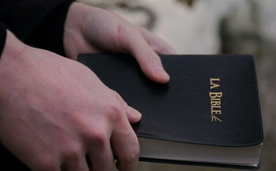 person holding black book on brown sand during daytime