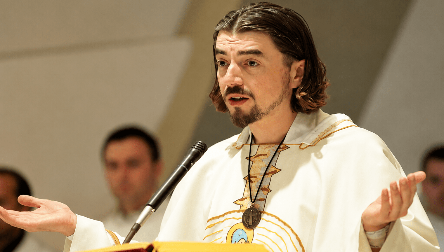 Vlč. Zlatko Sudac tijekom propovijedi govori vjernicima s raširenim rukama za ambonom u crkvi.