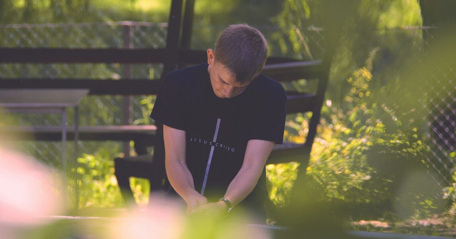 selective focus photography of sitting man wearing black cross graphic shirt