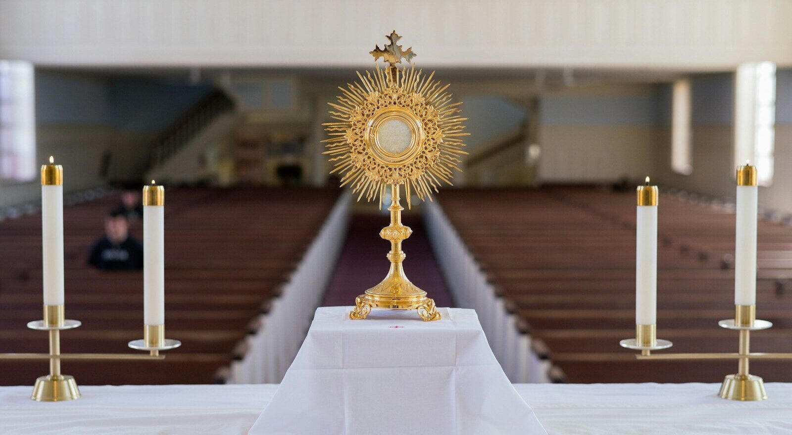 A golden monstrance with candles on an altar.