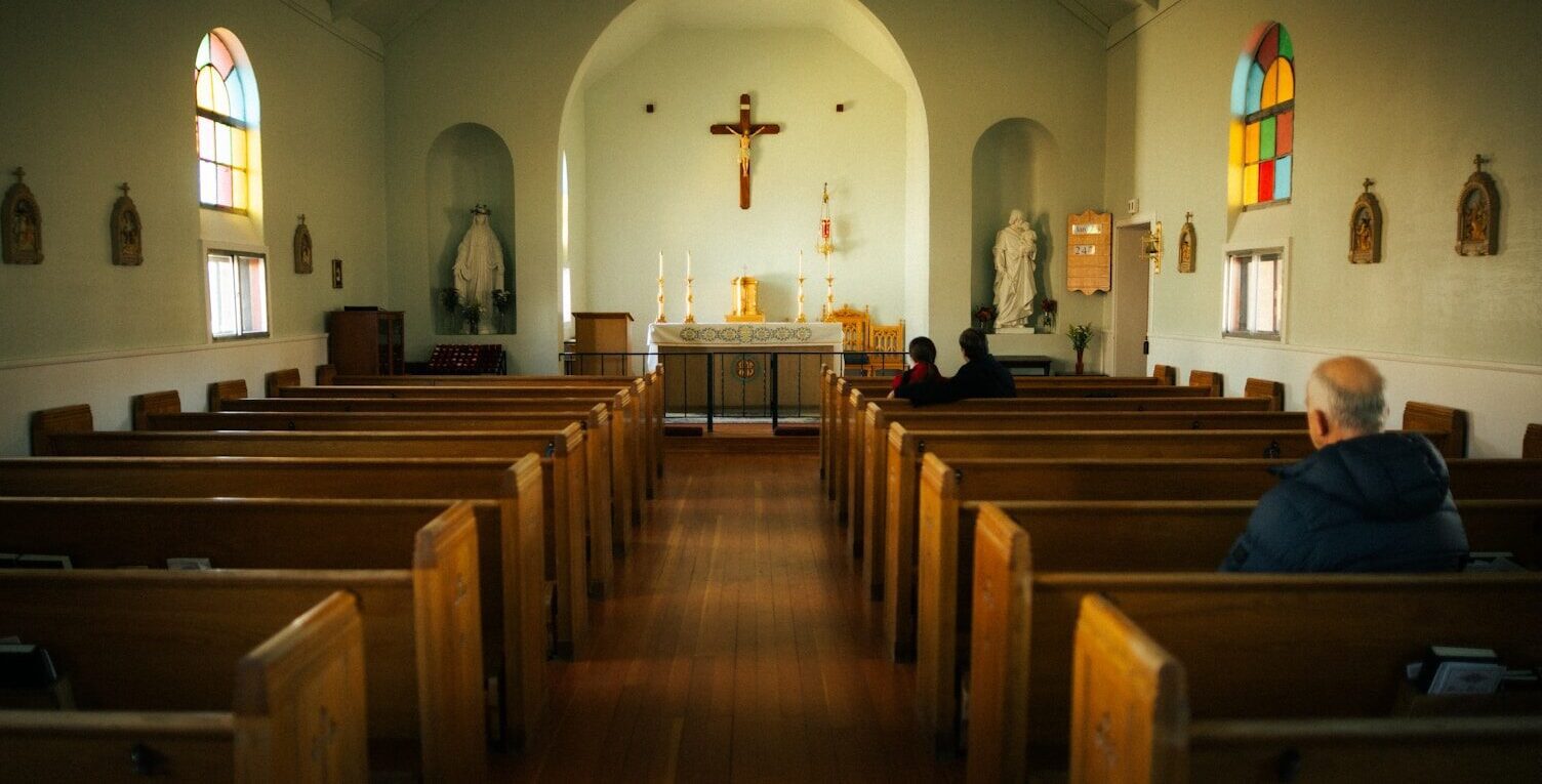 A man sitting in a church with stained glass windows