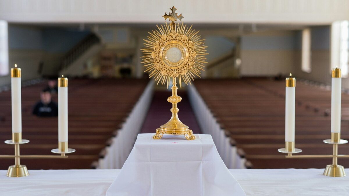 A golden monstrance with candles on an altar