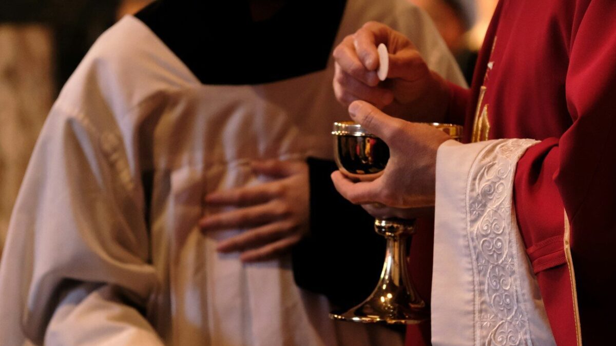 A priest is holding a glass of wine