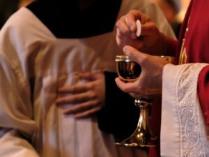 A priest is holding a glass of wine
