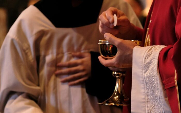 A priest is holding a glass of wine