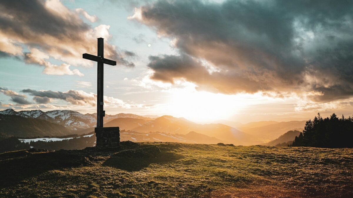 a cross sitting on top of a lush green hillside